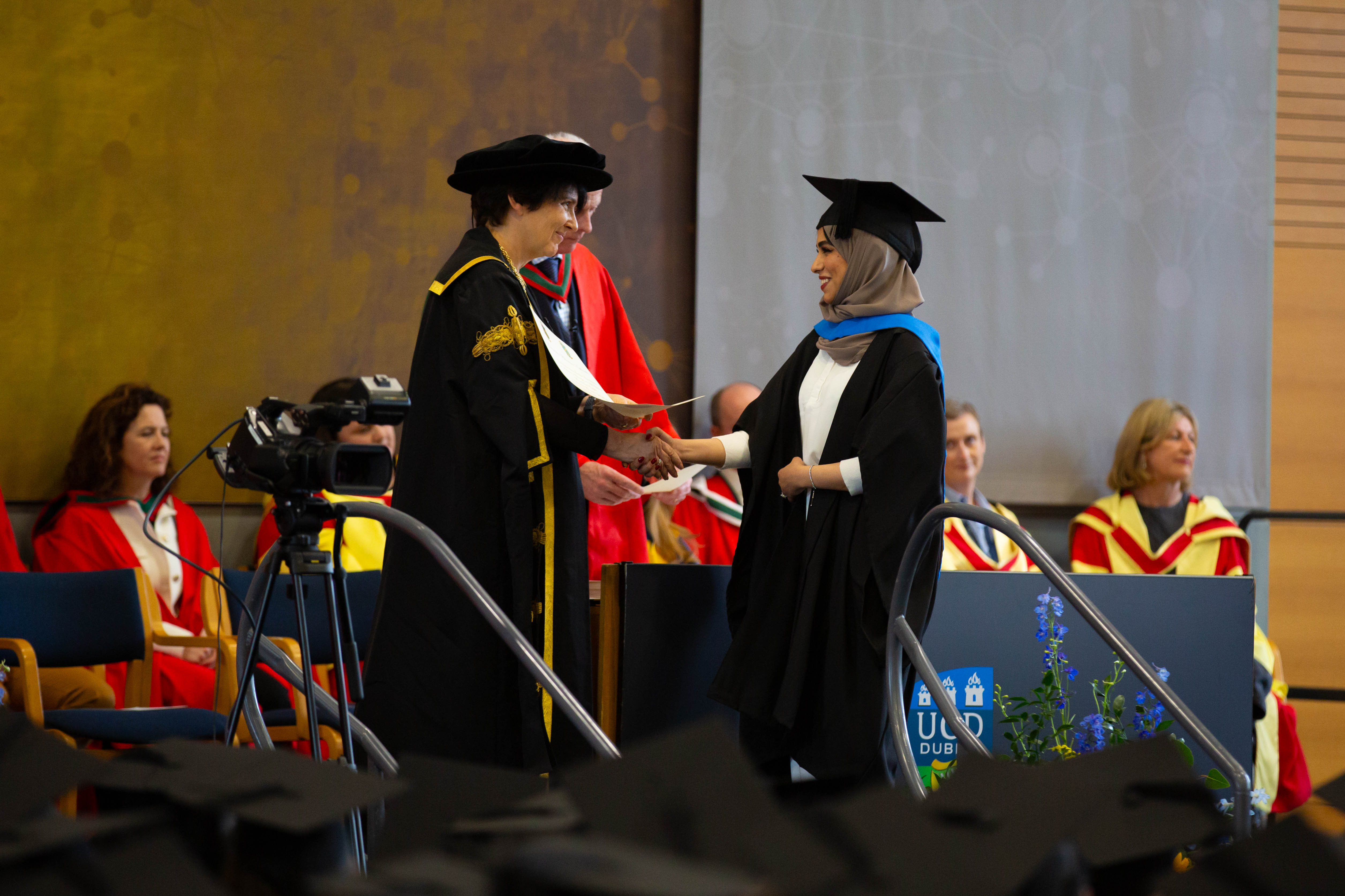 A student being presented their degree certificate on stage